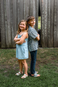 Brother and sister standing back to back during an outdoor family photography session in New Bern