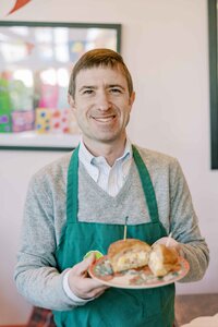Man smiling at the camera and holding a plate of breakfast foods from Ada's Cafe in Palo Alto