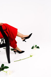 Creative portrait detail of legs in red styling against a bright studio background.