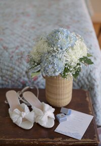 Close up details of wedding shoes with hydrangea bouquet.