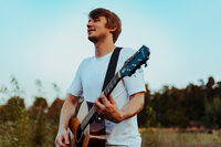 Musician holding a guitar during an outdoor creative portrait session