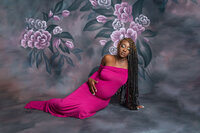Pregnant woman in a hot pink gown leaning against a textured wall during a Cleveland maternity photography session