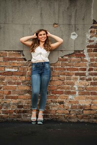 Senior portrait in downtown Mobile, Alabama — holding her hair up and standing right in front of a brick wall.