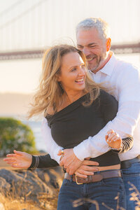 couple embracing sunset engagement photos by the golden gate bridge at cavallo point