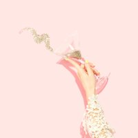 Lady tipping glass of gold glitter against pink background