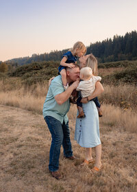 Family of 4 playing together in open field at Milo Mciver Park