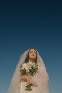 a bride under her veil illuminated by the sun with the blue sky behind her in austin, texas