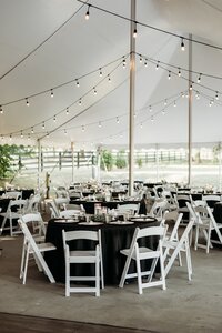 Reception tables set under a tent with string lights at Bradshaw Duncan House.
