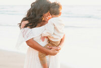 Family Photographer, a mother holds her young son at thebeach