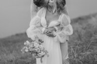 black and white image of groom kissing bride from hugging behind her in detroit
