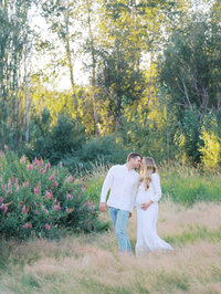 Couple in front of a flowering bush sharing a kiss