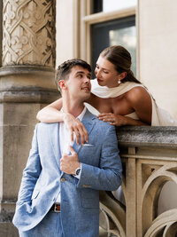 A couple embracing under a wisteria-covered stone terrace, illustrating the refined composition and heirloom imagery of an estate wedding.