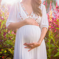 mom-to-be holds belly in white gown during maternity session