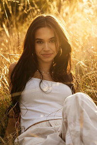 High school senior girl in a field in the summer during golden hour.