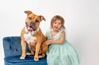 Young girl in blue dress seated with dog n New Bern photography studio