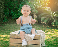 One year old baby seated on wooden crate in outdoor garden setting in New Bern NC