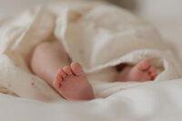 newborn-baby-feet-peeking-muslin-blanket-in-home-boulder-photographer-28