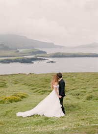 a bride standing next to an old castle during their ireland elopement