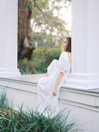 An expecting mom in Seattle sitting on the ledge of a porch looking out into her surroundings captured by Seattle Maternity Photographer Tanya Zagumenov