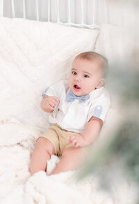 3 month old baby sitting in a cozy Christmas mini session set by miami christmas mini session photographer