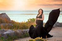 Expecting mother in flowing gown on sand dunes at sunset maternity session near Atlantic Beach NC