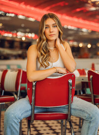 Senior portrait at Sunliner Diner in Gulf Shores, Alabama — sitting backward in a red diner chair.
