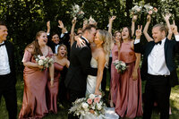 bride and groom kissing as wedding party celebrates
