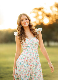 Senior portrait in downtown Magnolia Springs, Alabama — walking toward the camera with the sunset glowing behind her.