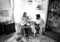 Jacksonville, FL portrait session capturing In Mandarin, a newborn rests in her mother’s lap while dad reaches down to the family dogs greeting their newest pack member during a lifestyle newborn.