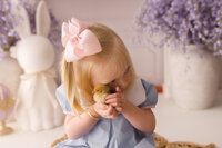 Toddler girl holds live baby chics during Easter Mini Session at Holy City Babies Portrait Studio in Charleston, SC.