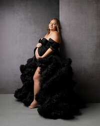 Pregnant woman wearing an elegant black tulle maternity gown during a studio maternity photography session by Kaitlyn Dawn Photography.