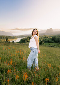 Girl getting senior portraits done in the Columbia River Gorge with a view of Beacon Rock and the Columbia River behind her.