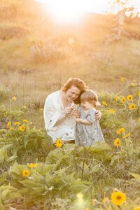 light-skinned dad holding up his toddler boy in the air in a field of golden grasses. Portland family photography session.
