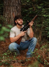 Senior portrait at Circle B Lake in Wilmer, Alabama — leaning against a pine tree holding an
unloaded hunting rifle in a ready position.