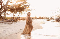 Folly Beach Maternity Photographer -- Pregnant woman poses for Maternity Photos at the Lighthouse Inlet Heritage Preserve on Folly Beach with iconic views of the Morris Island Lighthouse in the distance.