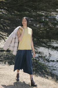 Chartreuse knit tank and navy skirt with a puffer carried over the shoulder, seasonal lookbook frame
