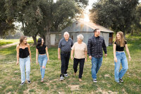 Multigenerational family walking together across a grassy field at sunset, relaxed and candid outdoor portrait by Kaitlyn Dawn Photography, lifestyle family photographer.