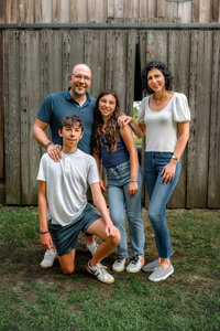 Family of four posing in front of a rustic wooden barn during a New Bern family photography session