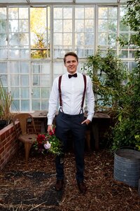 Groom standing in greenhouse during wedding portraits