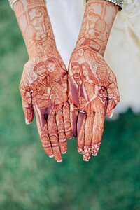 A person showcasing intricate henna designs on their hands, including a depiction of a couple.