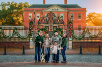 Family smiling at the camera in front of Tryon Palace during a downtown New Bern family session