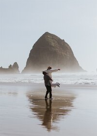 man lifting woman on oregon coast beach.