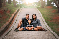 Parents sitting with their young son on a paved path during outdoor family portrait session in Eastern North Carolina