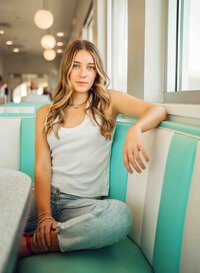 Senior girl sitting in a teal-and-white booth by a window at Sunliner Diner in Gulf Shores, Alabama.
