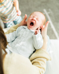 Newborn baby yawning while being held by mom during an in-home newborn photography session.