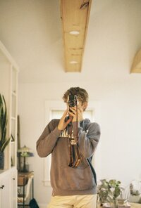 Sam Dykstra, gay photographer, posing with his film camera.