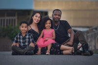 Modern family of four seated together in downtown setting during lifestyle family session