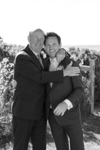 Father and Groom embrace for a family portrait.