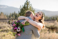 Bride laughing while embracing her groom during a mountain wedding photography session in Graeagle, California with Nature’s Child Photography, colorful bouquet and warm golden light surrounding the couple against a Sierra mountain backdrop.