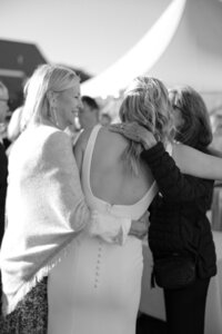 Bride is embraced by guests during cocktail hour.